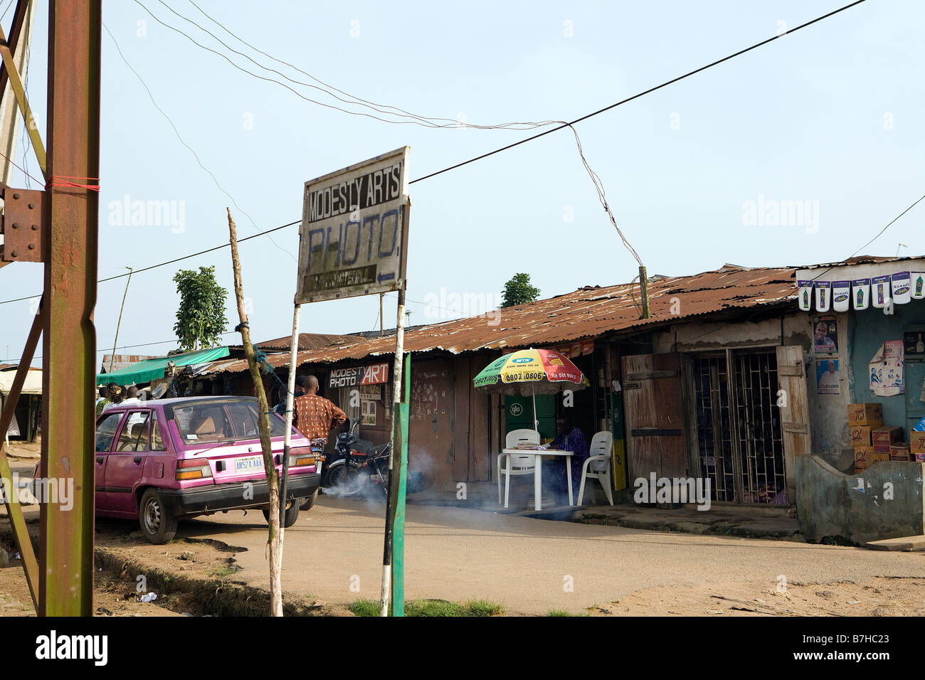 Eine Reihe von Menschen stehen in einer Straße in Epe, Nigeria, während ein anderer Mann sitzt und seinen Papierkram tut Stockfoto