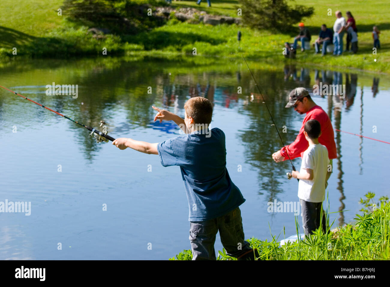 Ein Vater und seine Söhne, die in einem Teich angeln, während ein Angeln-derby Stockfoto