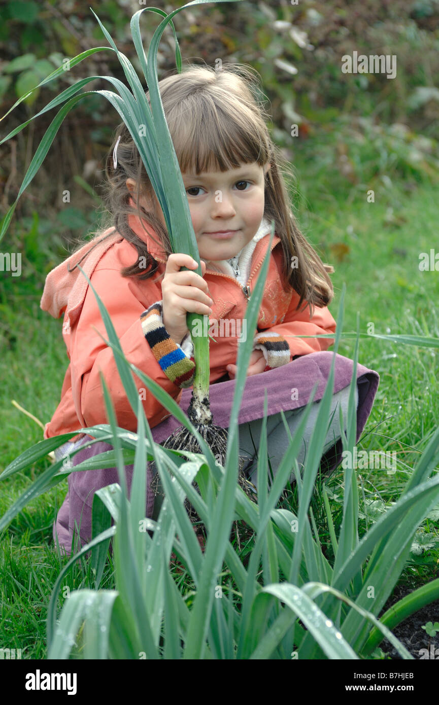 Ein Kind hält eine Lauch-Pflanze, die sie gerade gezogen hat, wachsen in ihrem Garten oder Zuteilung Stockfoto