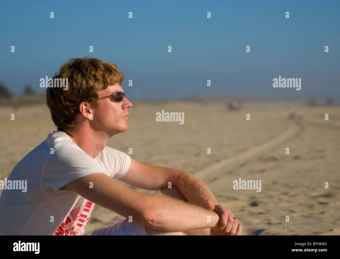 Junger Mann am Strand sitzen Stockfoto