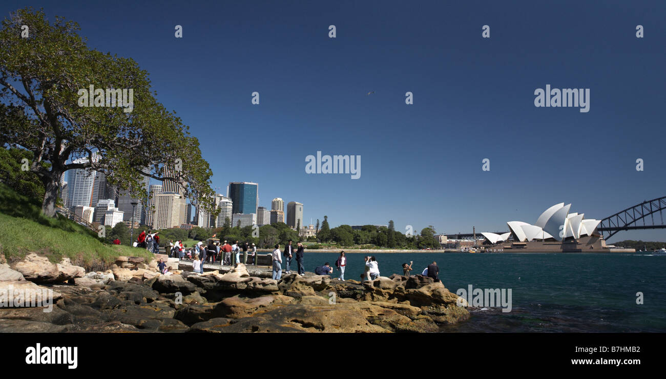 Gruppe von asiatischen Touristen vor Sydney Skyline mit Oper und zentraler Geschäftsbezirk von Mrs Macquaries Point. Stockfoto