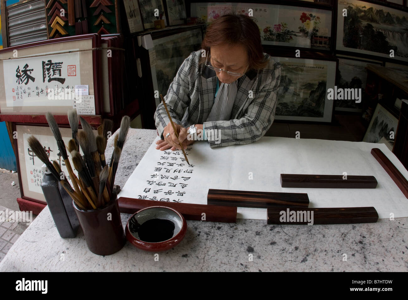 Chinesische artiest und Shop Besitzer sitzen schaffen ein neues Kunstwerk Stück mit chinesischen Kalligraphie Kanton Guangzhou Guangdong China Stockfoto
