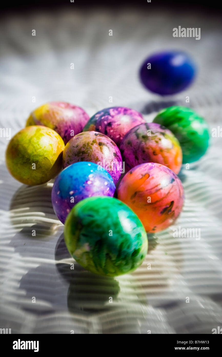 Eine Gruppierung von bunt bemalten und gefärbten Ostereier auf einen geflochtenen Tisch in der Sonne. Stockfoto