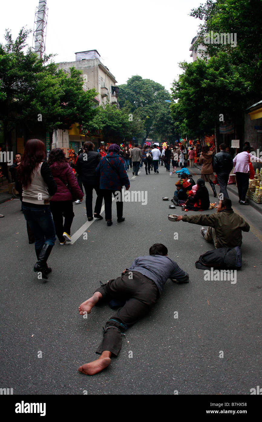 Menschen passieren Bettler auf der Straße in China auf dem Weg zum Tempel Stockfoto