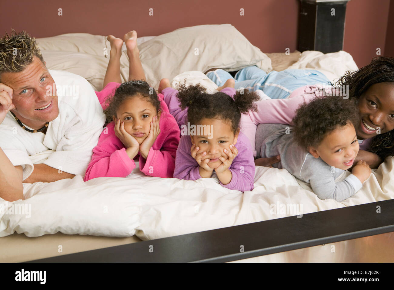 AA Mama, kaukasischen Papa, Mulatte Kinder, junge 1,5 Jahre, Mädchen 3 Jahre, Mädchen 6 Jahre. Im Bett. Stockfoto