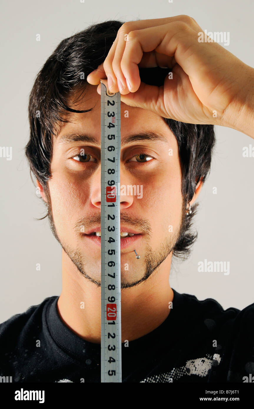 Porträt eines jungen Mannes mit Maßband über sein Gesicht Stockfoto