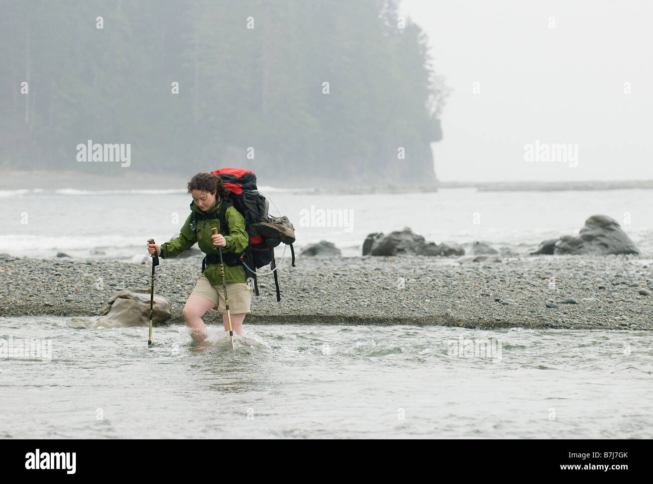 Frau (20-25) über einem schnell fließenden Bach mit einem großen Rucksack auf, West Coast Trail, Pacific Rim National Park Reserve, BC Stockfoto