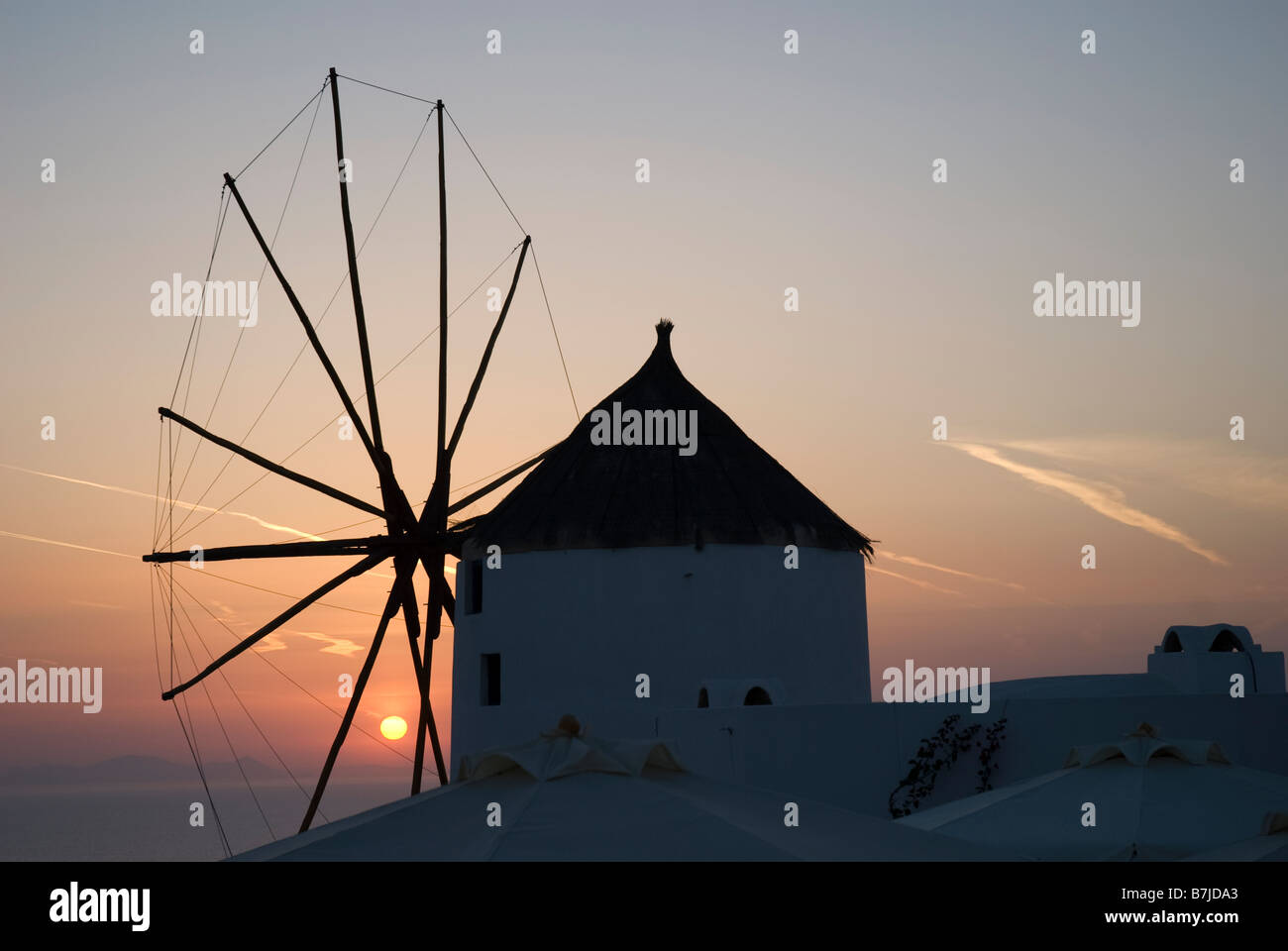Sonnenuntergang hinter einer Windmühle in der Stadt Oia, Santorini, Griechenland Stockfoto