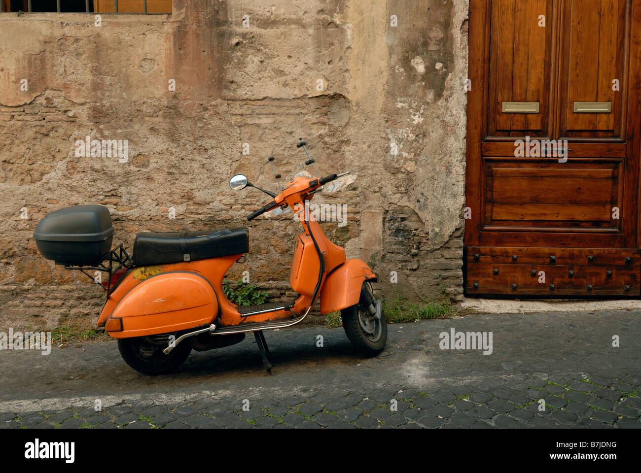 Orange Scooter geparkt in alten Gasse von Trastevere Rom Italien Stockfoto
