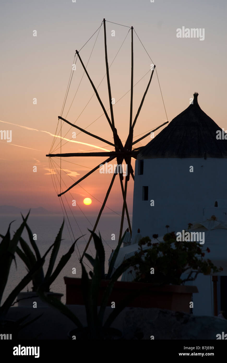 Sonnenuntergang hinter einer Windmühle in der Stadt Oia, Santorini, Griechenland Stockfoto