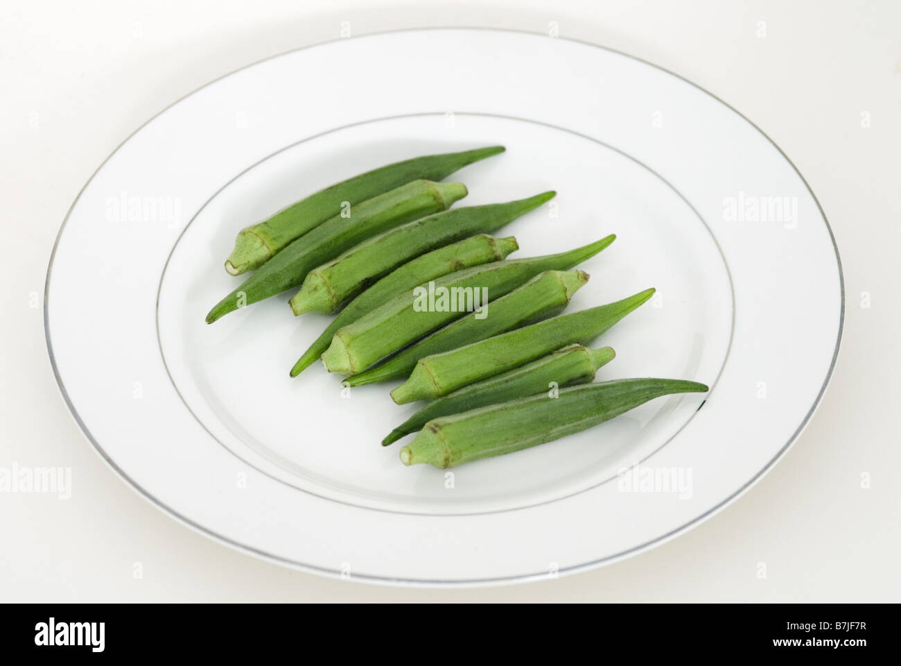 ABELMOSCHUS ESCULENTUS OKRA AUF WEIßEN TELLER Stockfoto