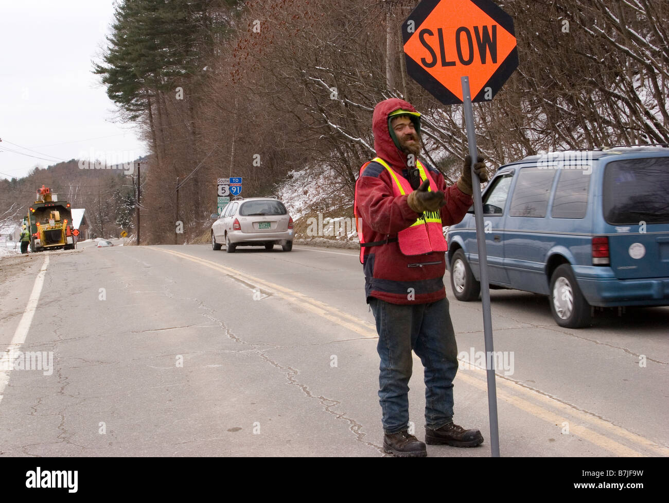 Flagger Straßenarbeiter hält Verkehrszeichen in der Mitte der Straße Stockfoto