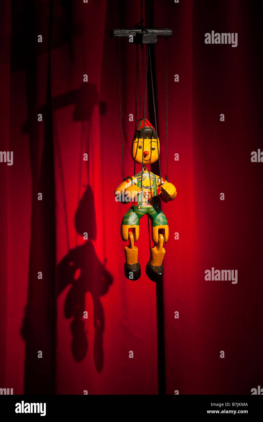Hölzerne Marionette Pinocchio hängt vor roten Vorhang Stockfoto