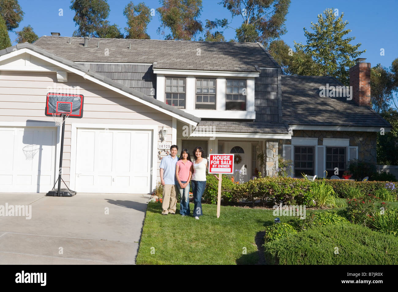 Familie stehen außen Haus mit Schild von Immobilienmakler Stockfoto