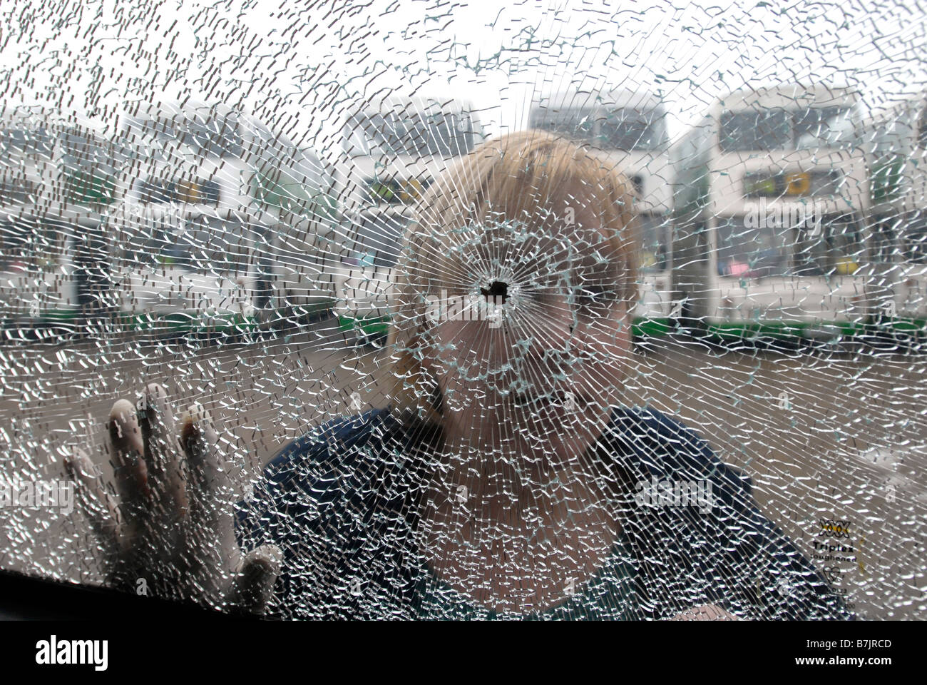 Eine Frau schaut durch zerbrochene Sicherheitsglas nach einem Angriff auf einen bus Stockfoto
