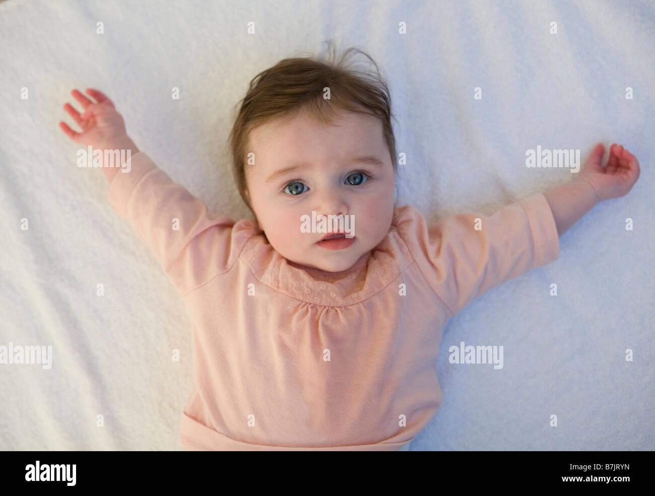 Ein sechs Monate altes Baby Mädchen mit ausgestreckten Armen. Stockfoto