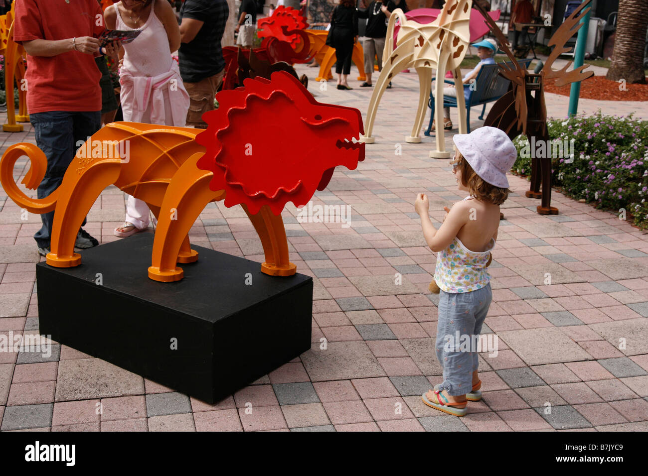 Junges Mädchen 4-6 Jahre alt ist neugierig und fasziniert durch eine Skulptur eines Metall Löwen. Stockfoto