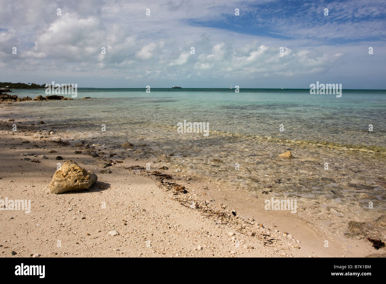 großer Felsen sitzen an einem tropischen Strand mit ruhigen türkisfarbenen Meer Stockfoto