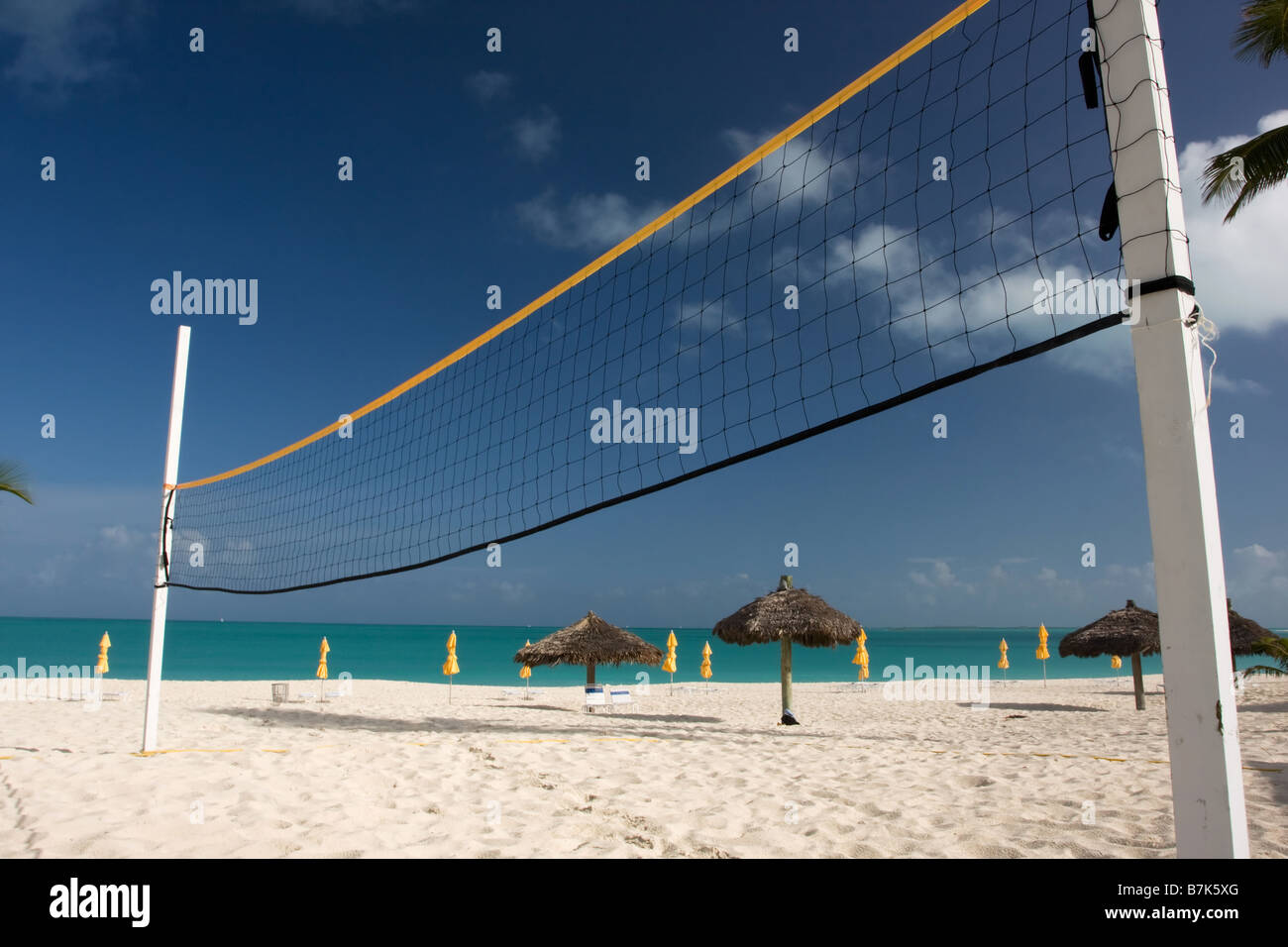 Beach-Volleyball Netz mit Sonnenschirmen und das türkisblaue Meer Stockfoto