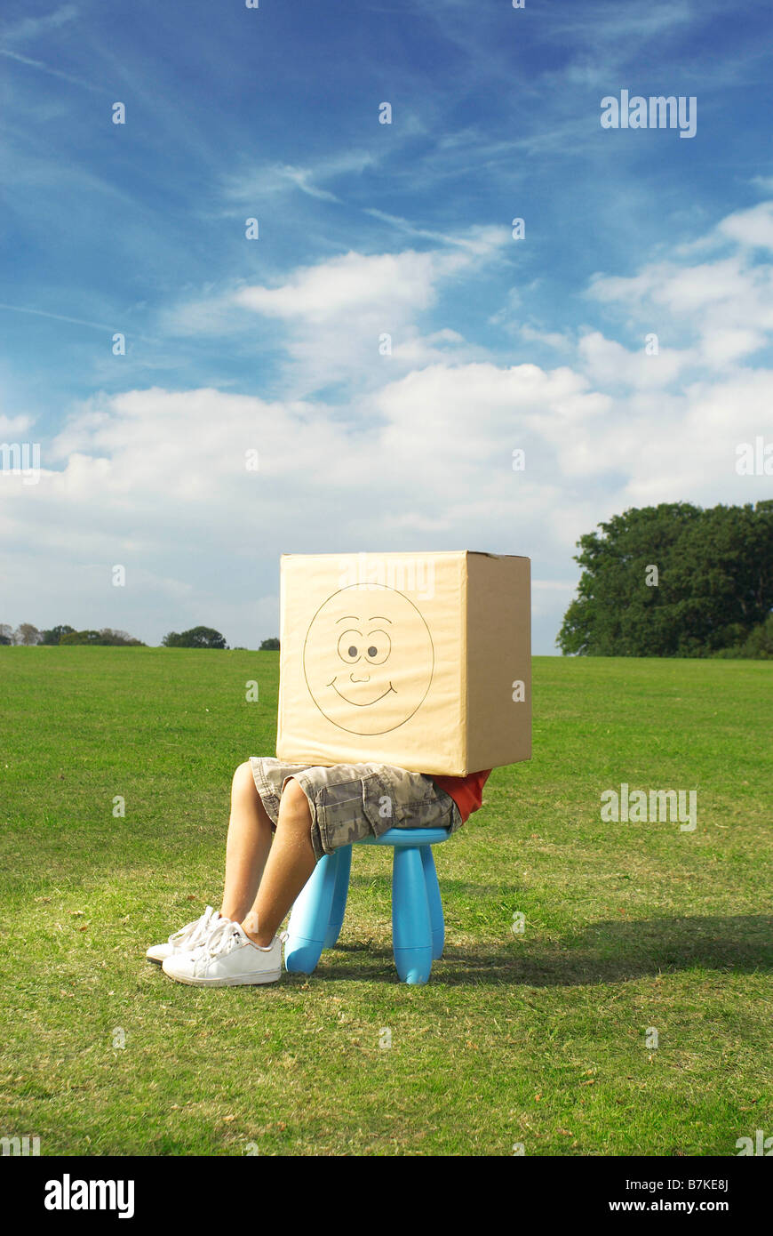 Junge auf Hocker mit Box auf Kopf Stockfoto