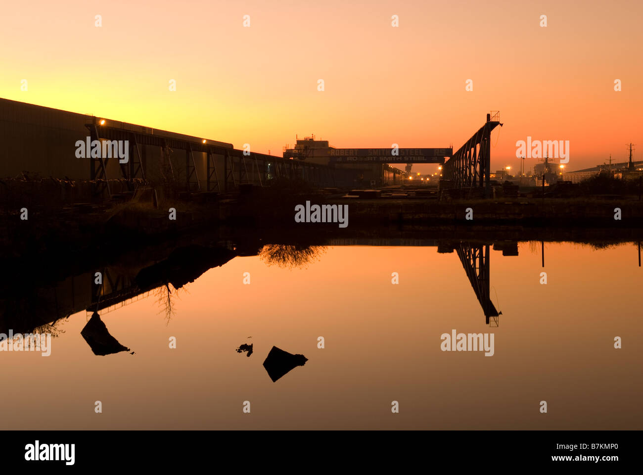 Reflexion der Sonnenuntergang über industrielle Docklands. Warme orange Leuchten Stockfoto