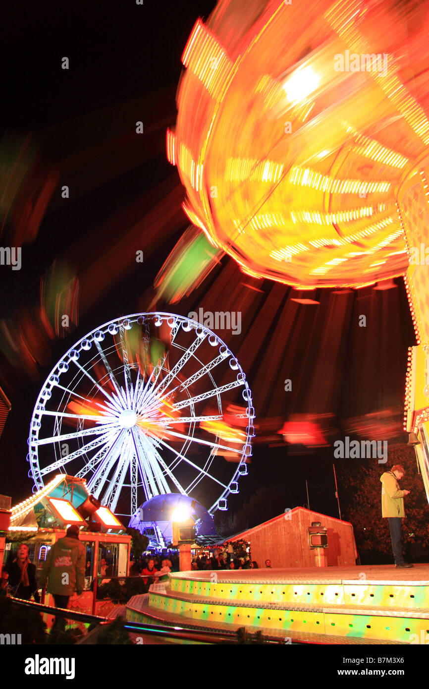 Beleuchtete traditionelle merry Go runden Stil Messegelände fahren und Riesenrad, Winter Wonderland, Hyde Park, London Stockfoto