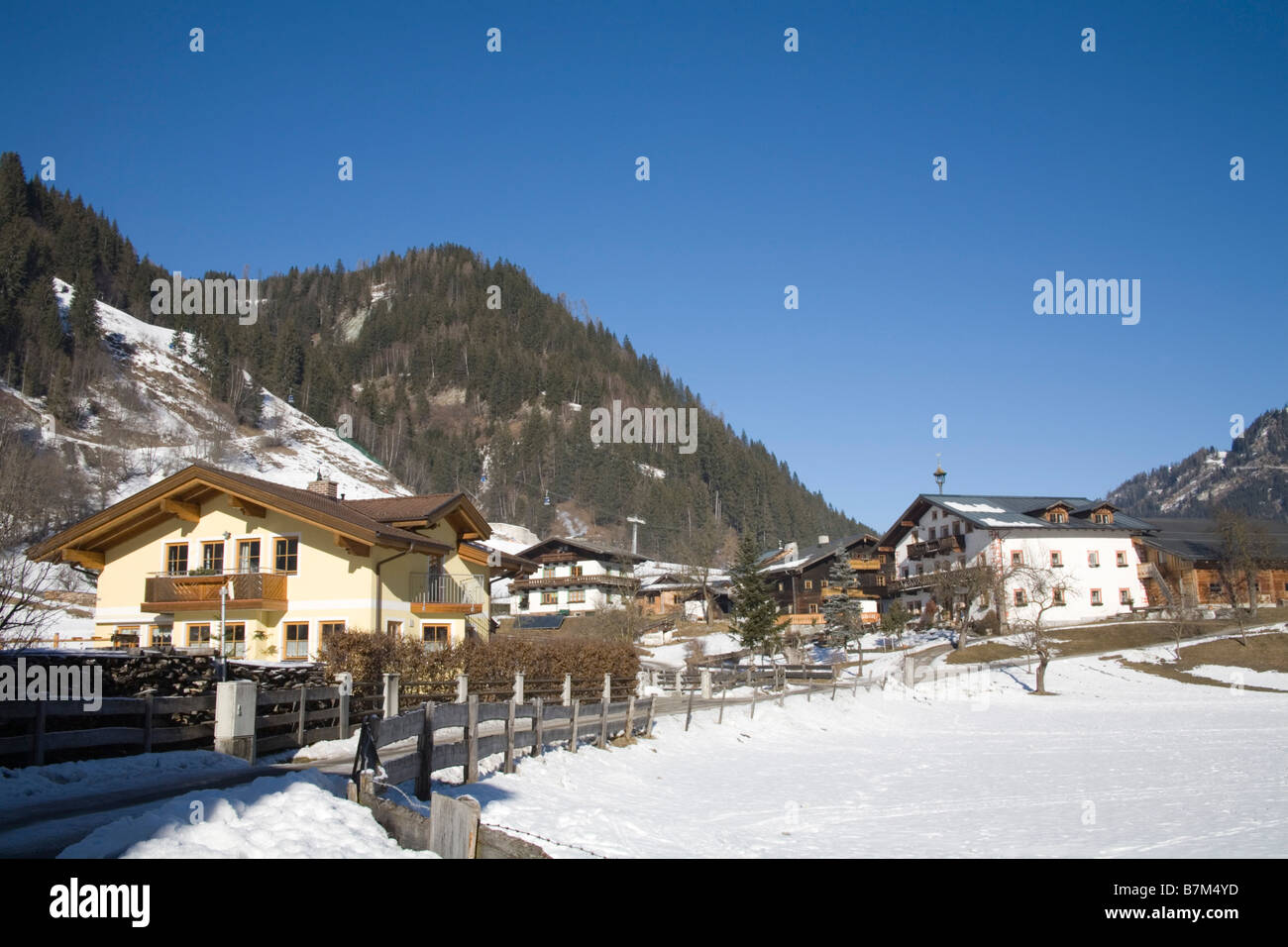 Rauris Österreich EU Januar Häuser in diesem traditionellen Wintersportort mit dem Skilift zum Skigebiet Sonniblick Berge an einem schönen Wintertag Stockfoto