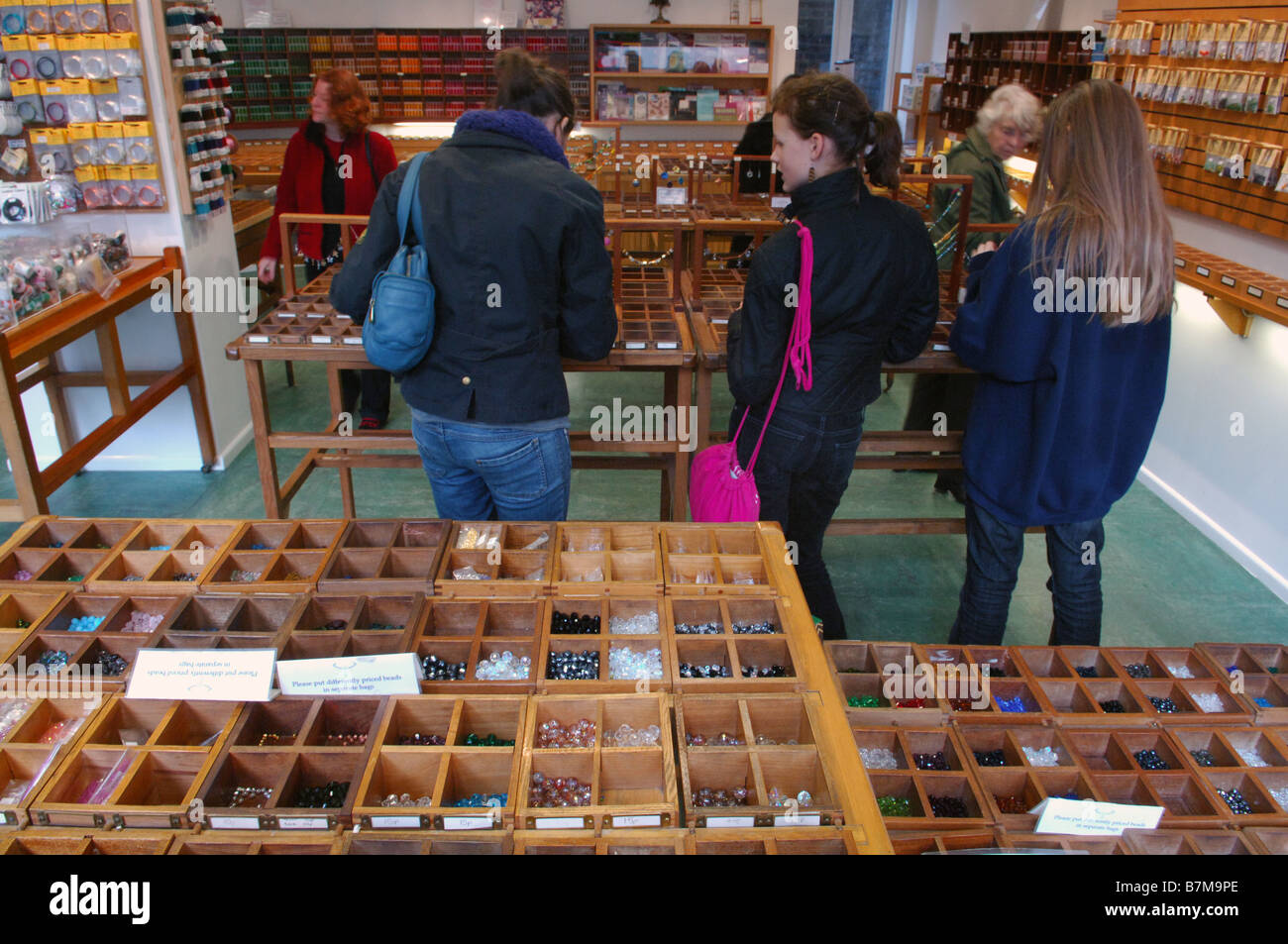 Mehrere Frauen und Handwerk-Enthusiasten stöbern und entdecken Sie verschiedene Perlen zu verkaufen. Stockfoto