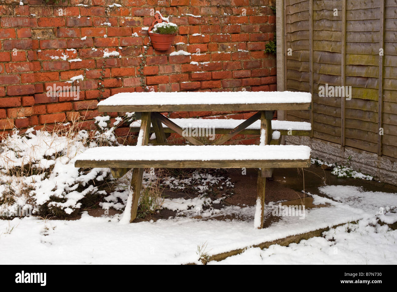 Gartentisch aus Holz oder Bank im Vereinigten Königreich Schnee im Winter überdacht Stockfoto