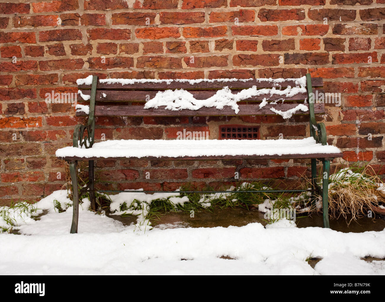 Alte Gartenbank Bank im Schnee in einem englischen Garten im Winter überdacht Stockfoto