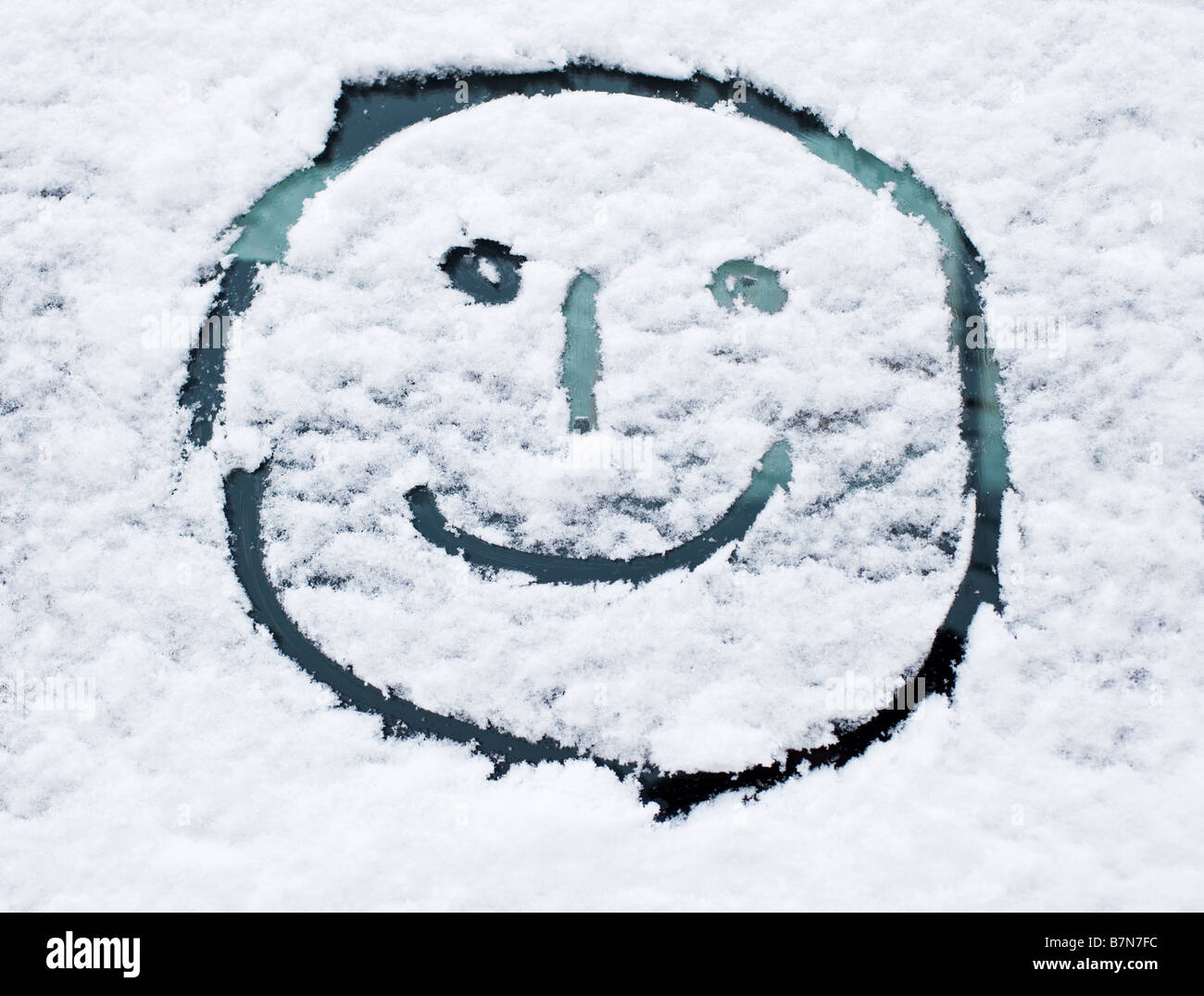 Winterschnee - Smiley-Gesicht gezeichnet im Neuschnee auf einer Auto-Windschutzscheibe Stockfoto