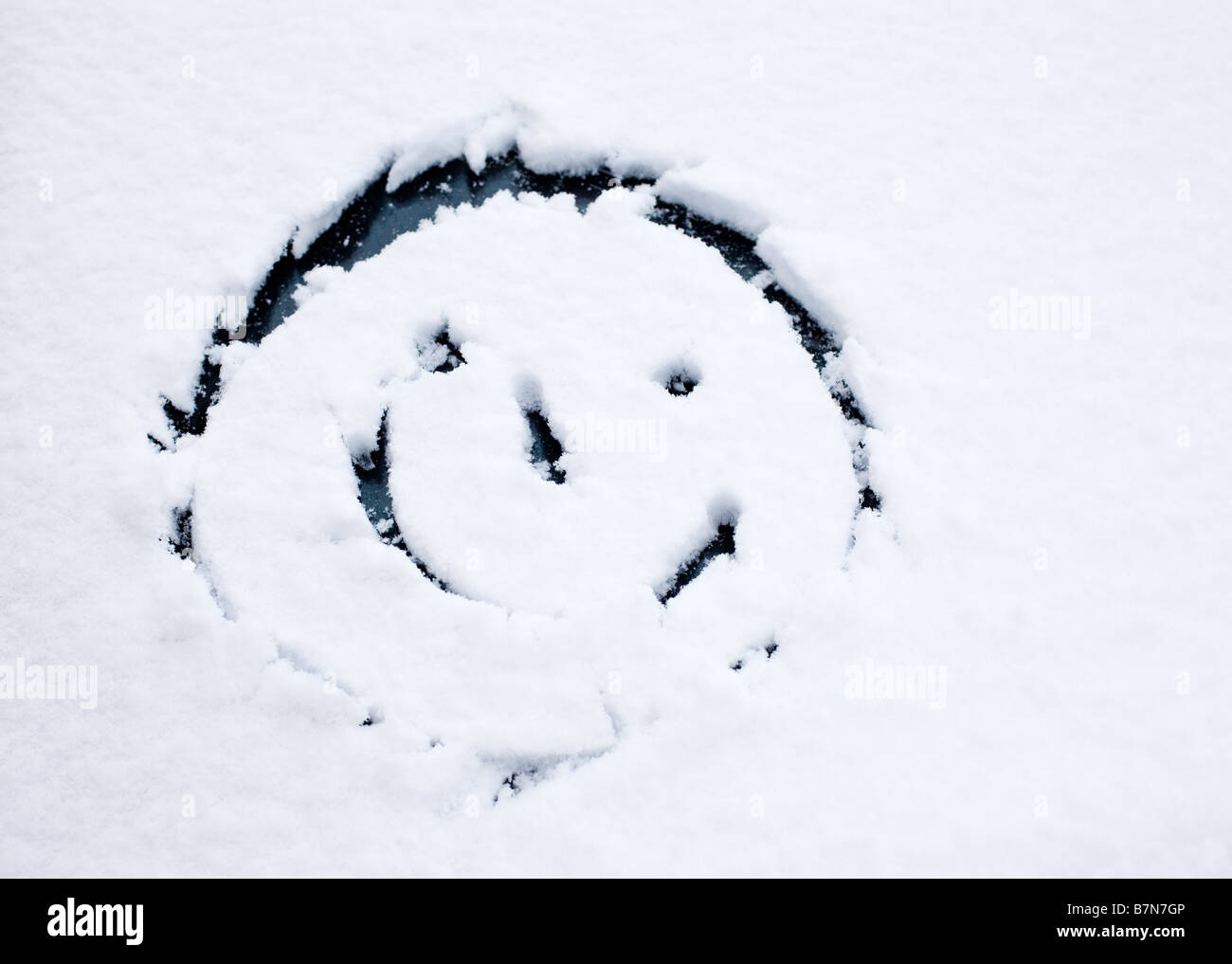 Smiley-Gesicht gezeichnet im Neuschnee auf einer Auto-Windschutzscheibe Stockfoto