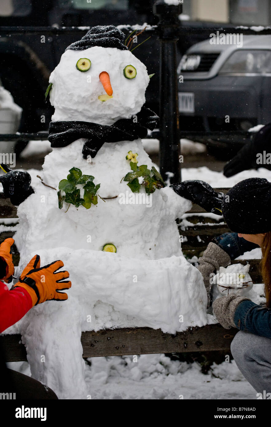 Letzten Schliff auf einem Schneemann und Snowcat sitzt auf einer Parkbank Stockfoto
