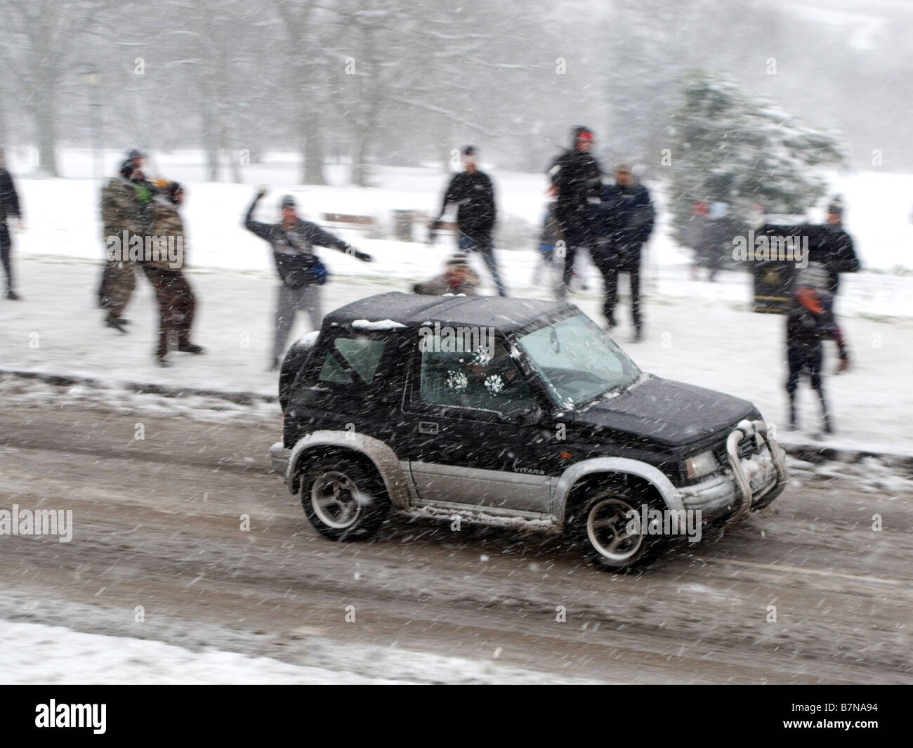 Jugendliche werfen Schneebälle auf vorbeifahrenden Fahrzeug Stockfoto