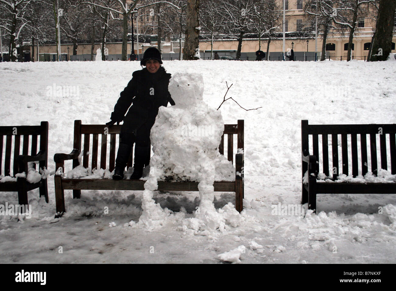 Sitzen auf einer Parkbank neben einen Schneemann Stockfoto