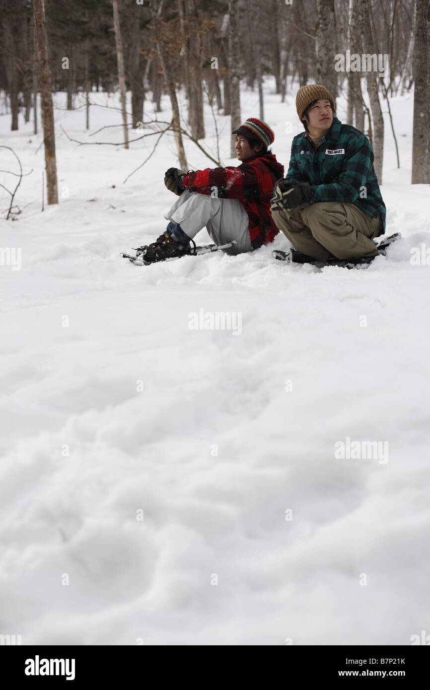 Freunde sitzen auf Schnee Stockfoto