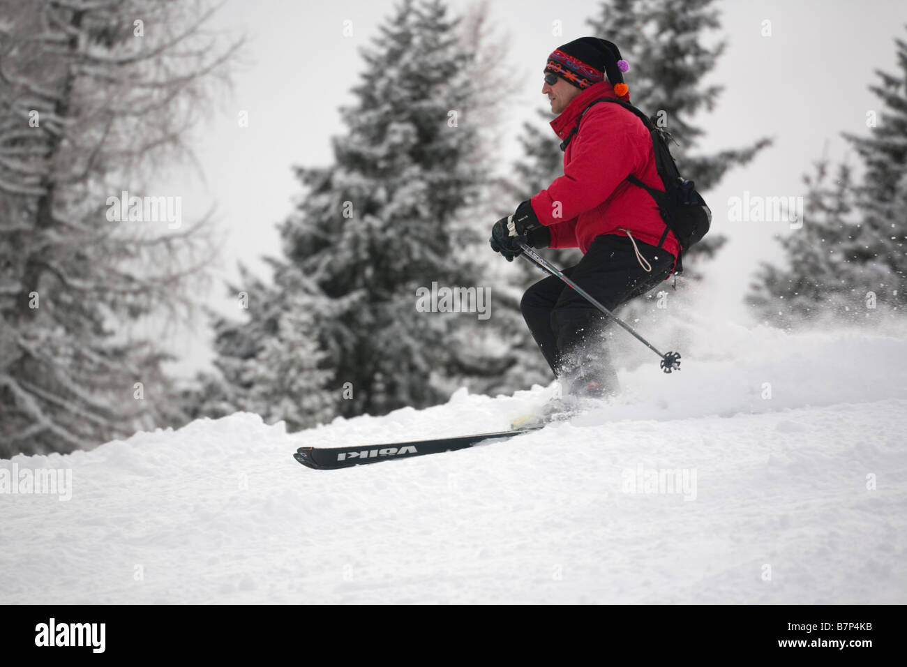 Männlichen Skifahrer trägt eine rote Jacke Skifahren schnell auf einem Berghang im Pulverschnee auf Piste in Österreichische Alpen. Österreich, Europa. Stockfoto