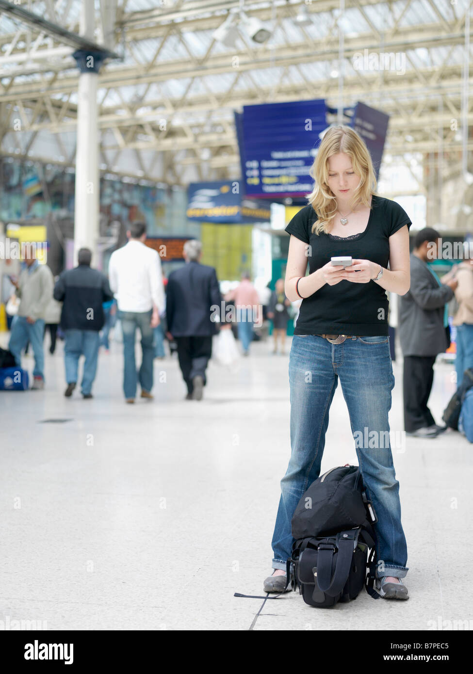 Eine junge Frau, überprüft ihr Telefon in die Liverpool-Bahnhof in London, England. Stockfoto