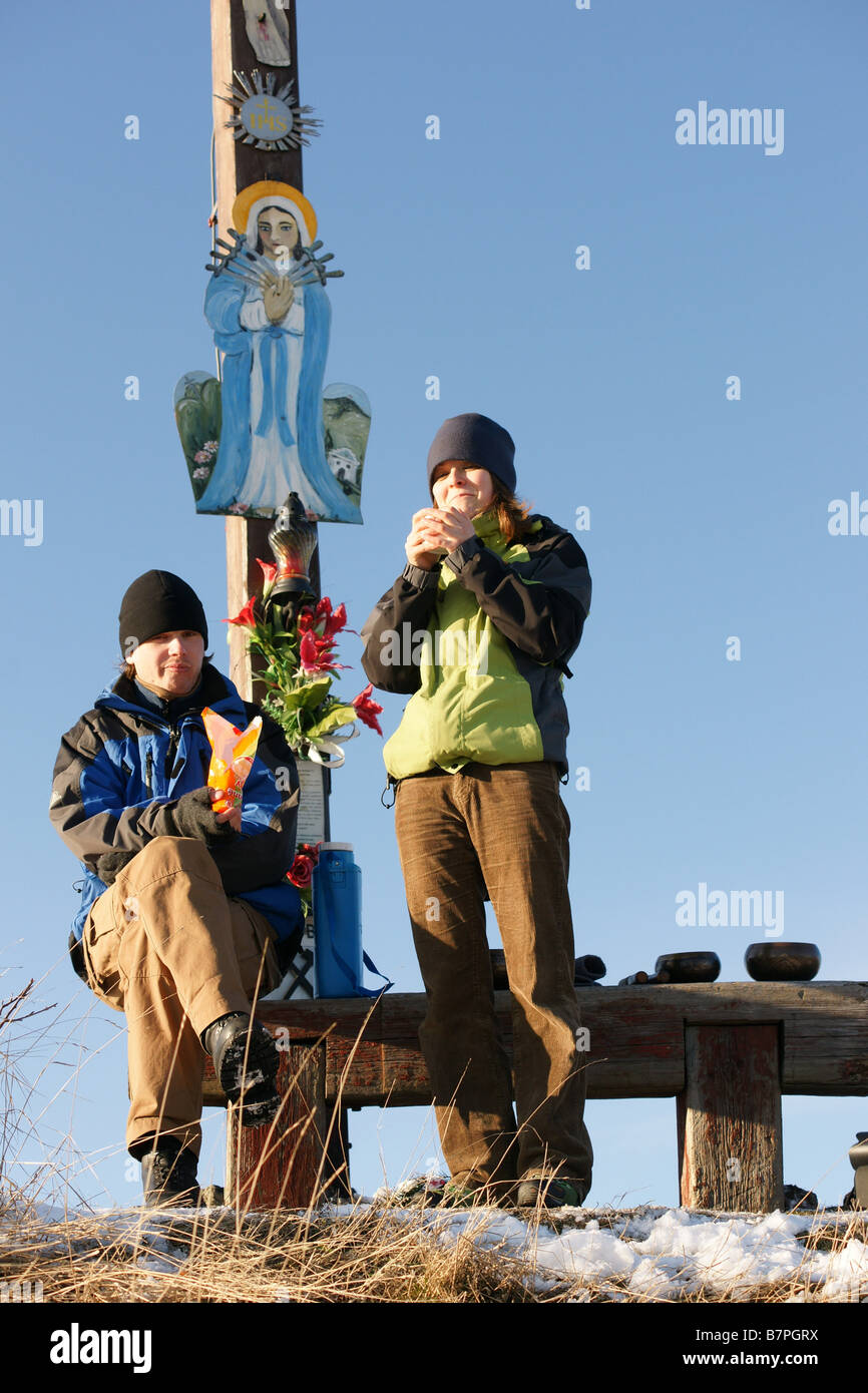 Junge Mädchen Touristen trekking sitzen auf Holzbank unter Kreuz auf Hügel Tanad im Winter Slowakei geschnitzte Stockfoto