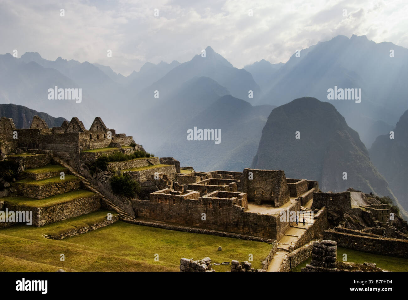 Zwei Besucher sind in den Schatten gestellt durch die Ruinen von Machu Picchu, eine alten Inka-Stätte thront über dem Urubamba-Tal. Stockfoto