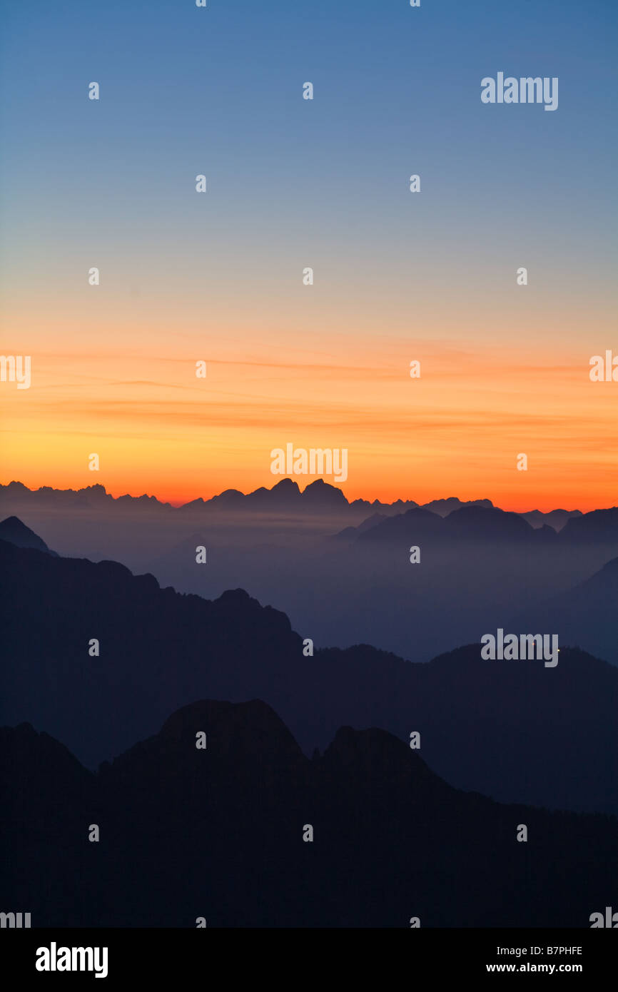 Julischen Alpen gesehen von Mangrt in Slowenien dunklen Bergen in Vordergrund mit reichen orange Sonnenuntergang zum Horizont und vor Stockfoto