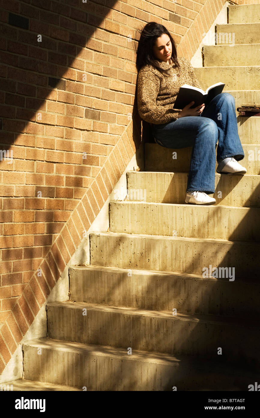 Frau Lesebuch auf Treppe Stockfoto