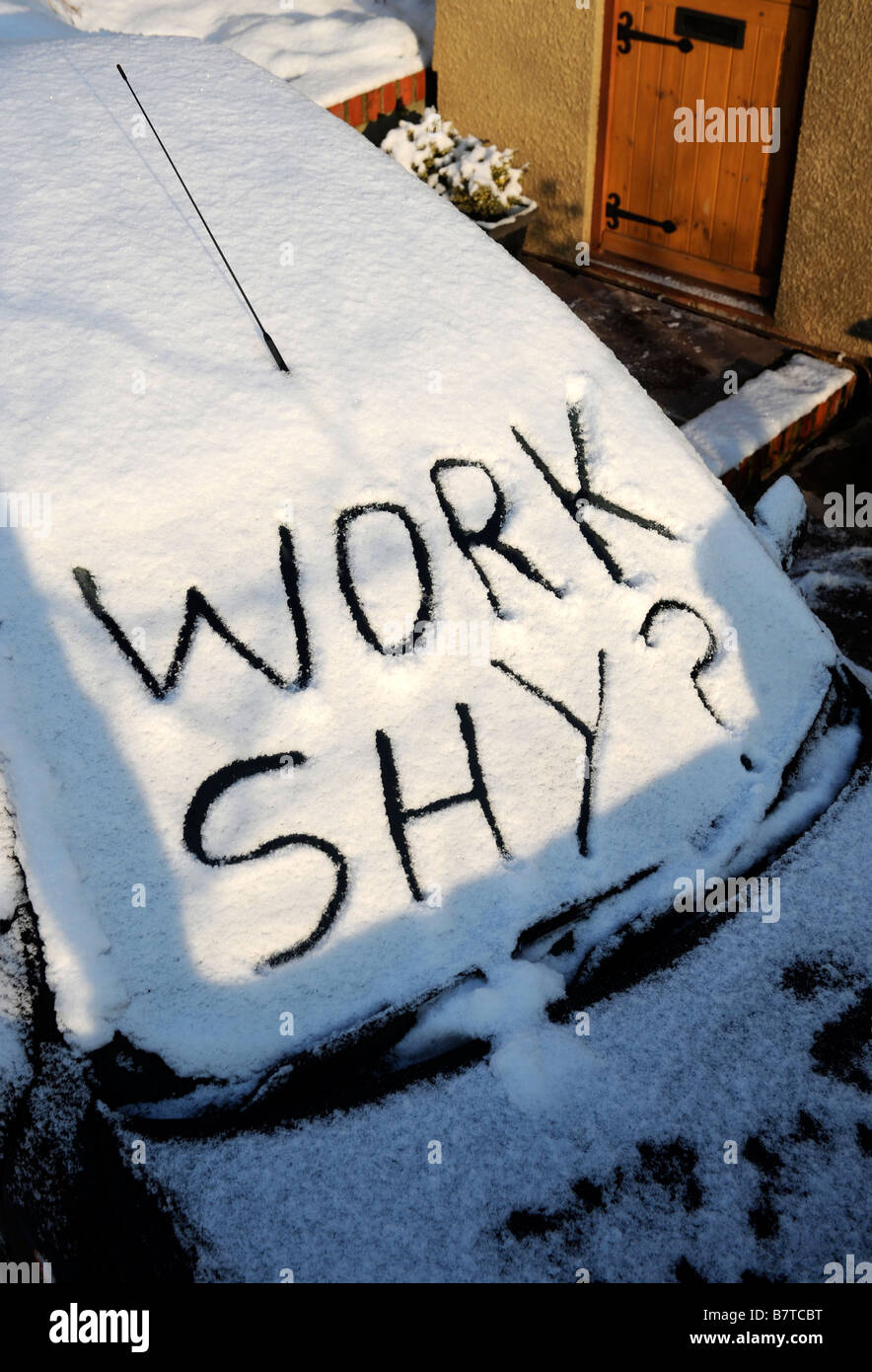 AUTO AUF EINER EINFAHRT MIT WORTEN ARBEITEN SCHÜCHTERN SCHRIFTLICHE IN SCHNEE DARAUF HINDEUTET ABWESENHEIT VON DER ARBEIT BEI MODERATEN WINTERLICHEN BEDINGUNGEN Stockfoto