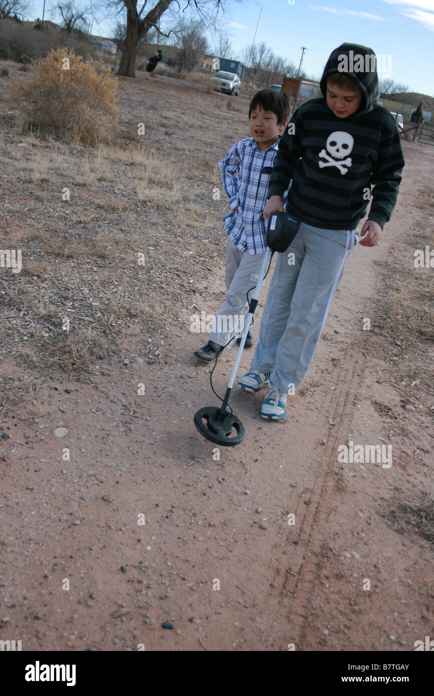 Kind mit einem Metalldetektor auf ein Feld zu Fuß mit einem Freund auf der Suche nach schätzen Stockfoto