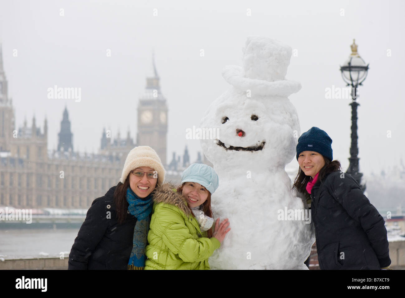 Touristen, posiert mit Schneemann auf Albert Embankment London Vereinigtes Königreich Stockfoto