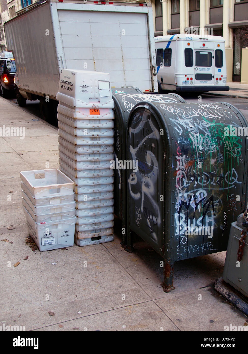 Gewellte Kunststoff-Behälter gestapelt neben zwei Briefkästen Lagerung in Graffiti auf dem Bürgersteig in New York City bedeckt. Stockfoto