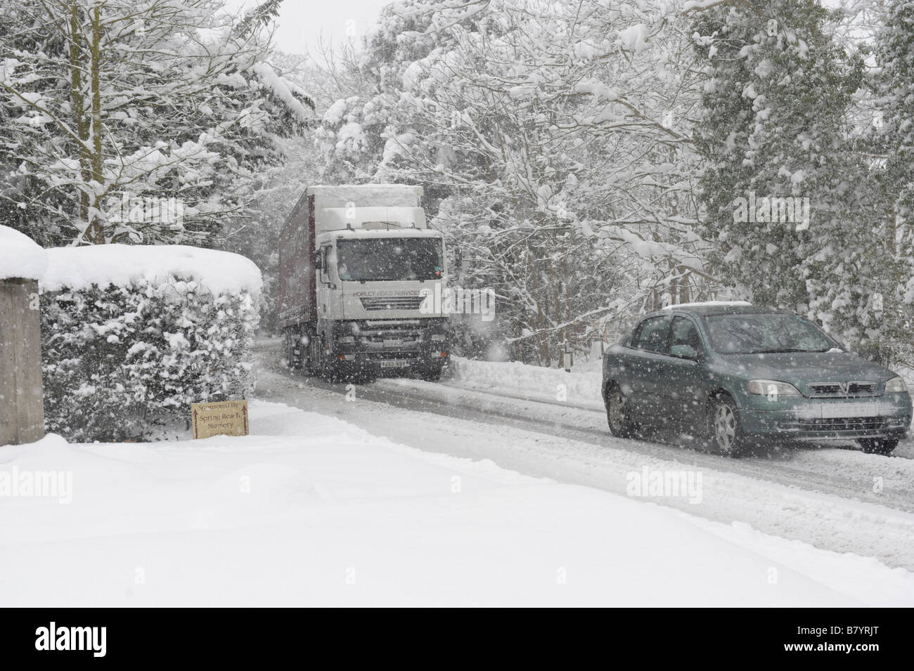 Ein Pkw und ein LKW verhandeln Schneefall auf einer Landstraße Stockfoto