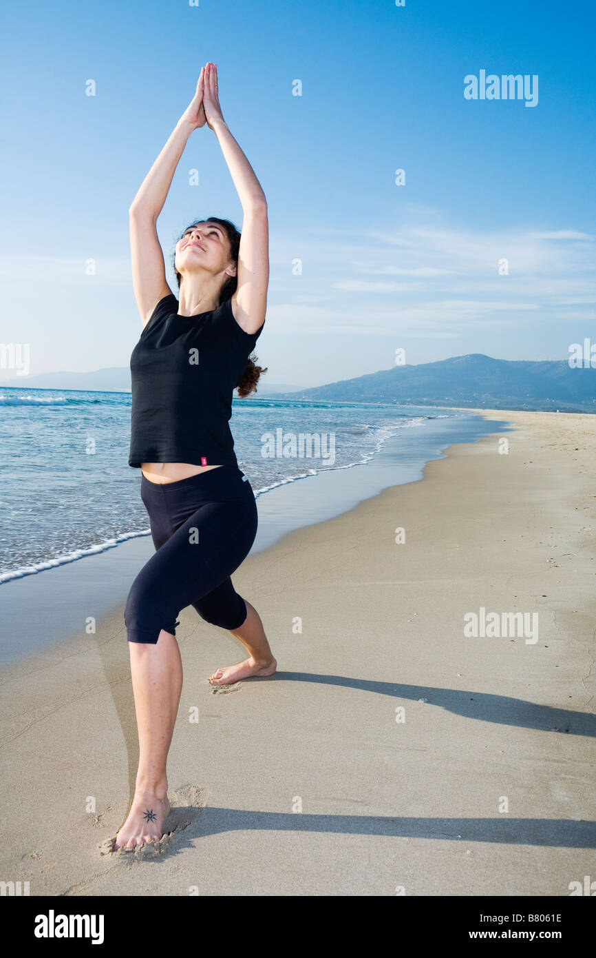 Junge Frau beim Yoga am Strand Stockfoto