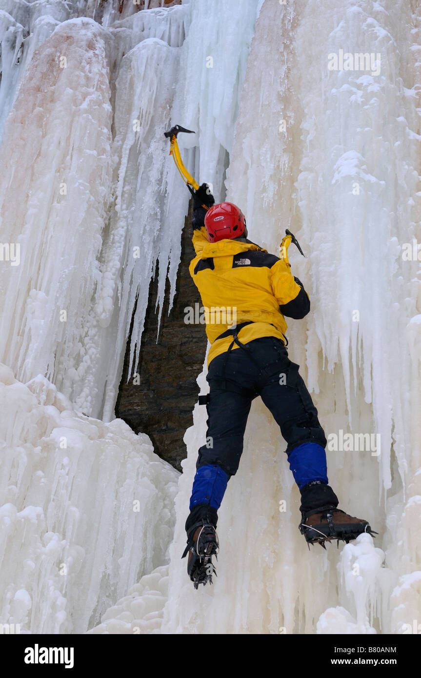 Eiskletterer schwingenden Axt mit kampflos auf eine vertikale Blatt des Eises bei Tiffany Falls Ontario Stockfoto Eiskletterer schwingenden Axt mit kampflos auf eine vertikale Blatt des Eises bei Tiffany Falls Ontario Stockfoto