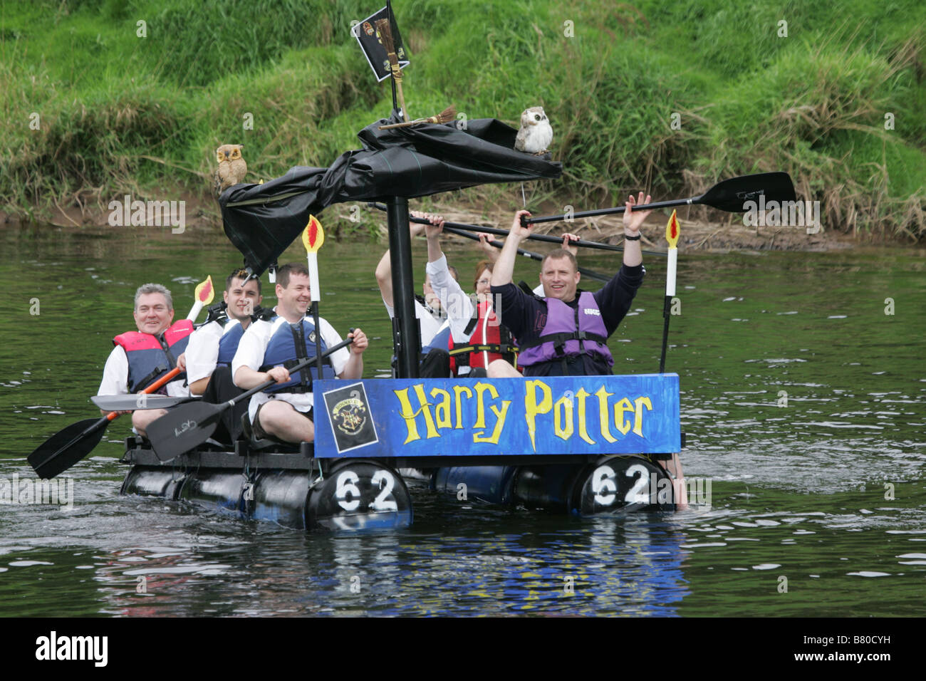 Monmouth Raft Race Teilnehmer auf ihrem Floß Kostüm tragen bringen Floß in Bank am Ende des Rennens. Stockfoto